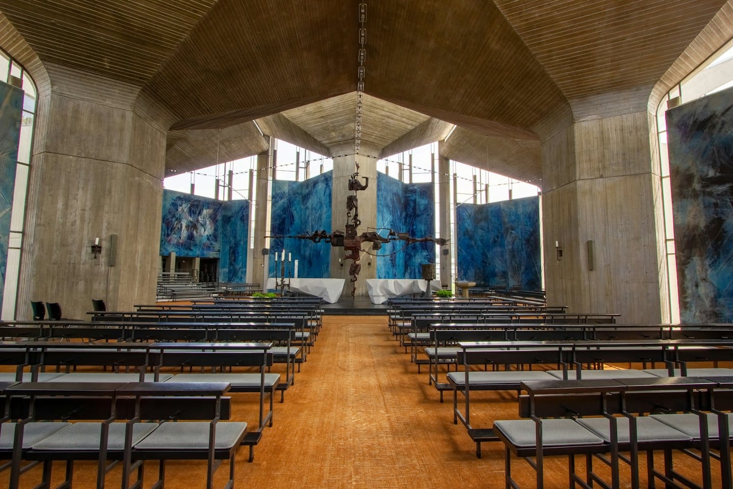 Interno di chiesa modernista con file di panche rivolte verso l'altare.