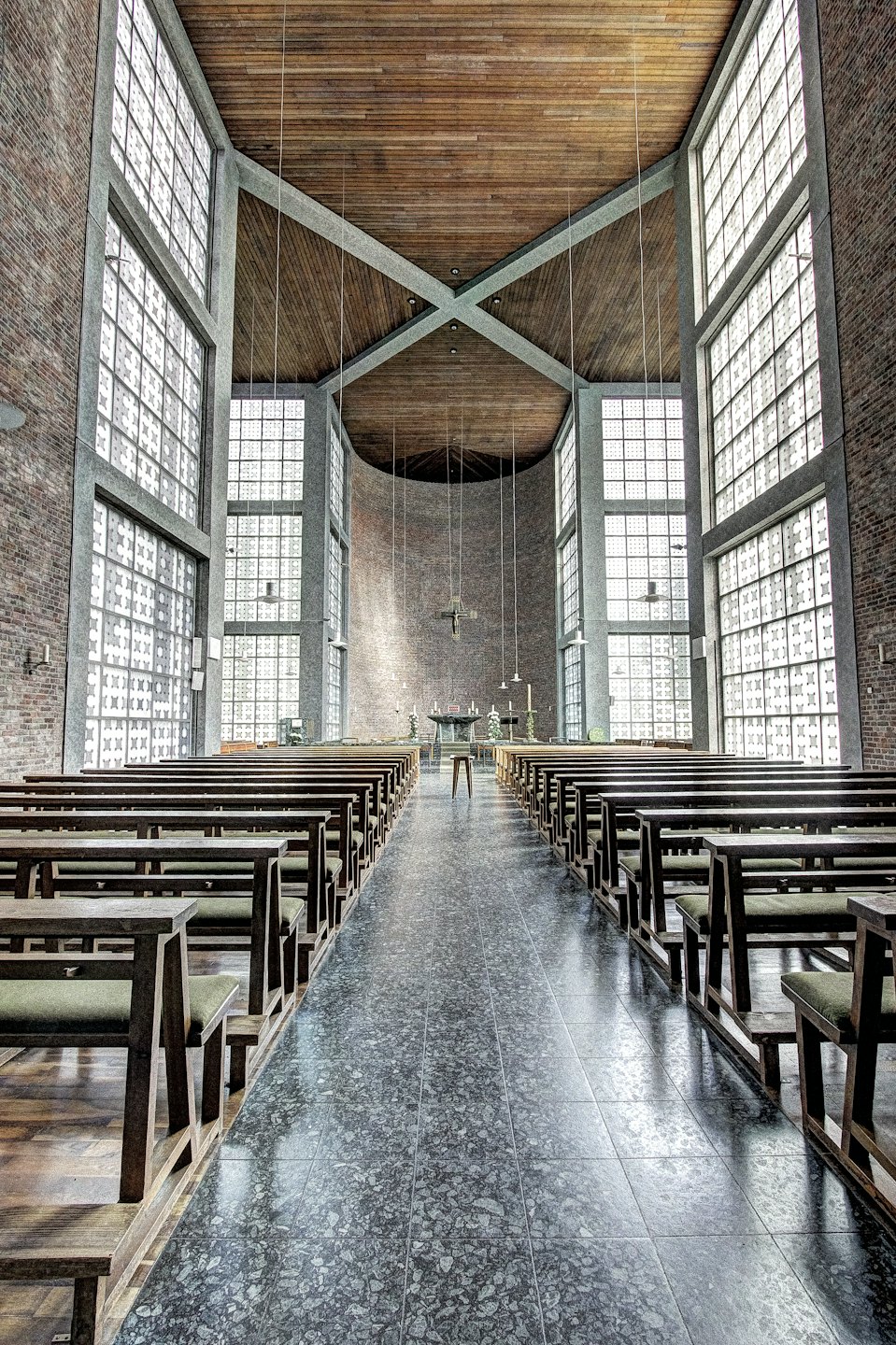 Interno di una chiesa moderna con file di panche rivolte verso una croce di legno.