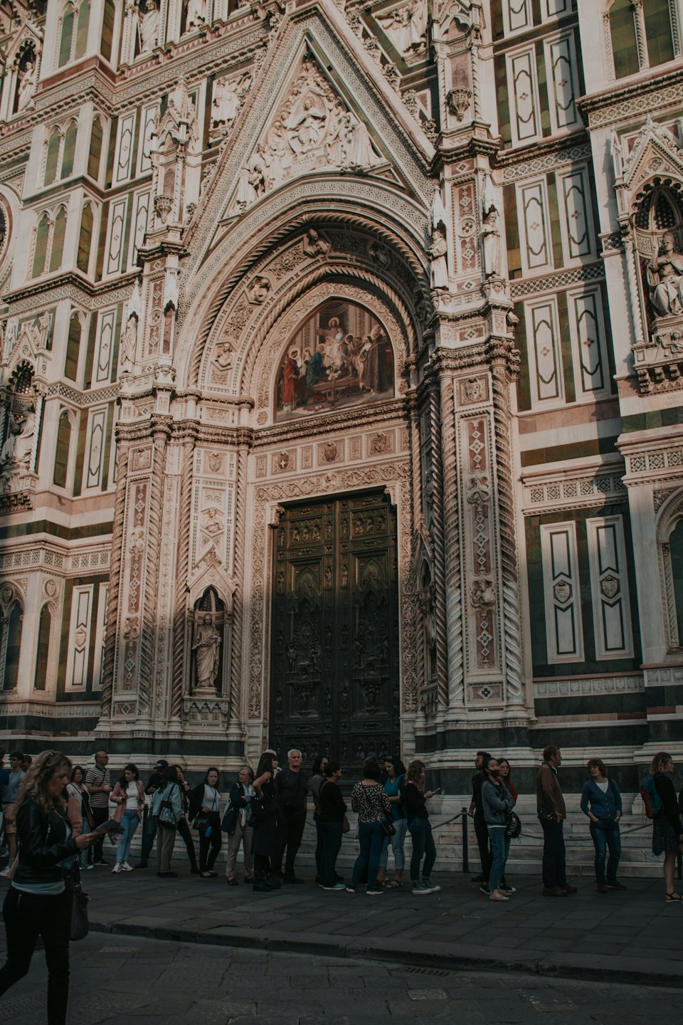 Un gruppo di visitatori si trova davanti a un'antica chiesa ornata.