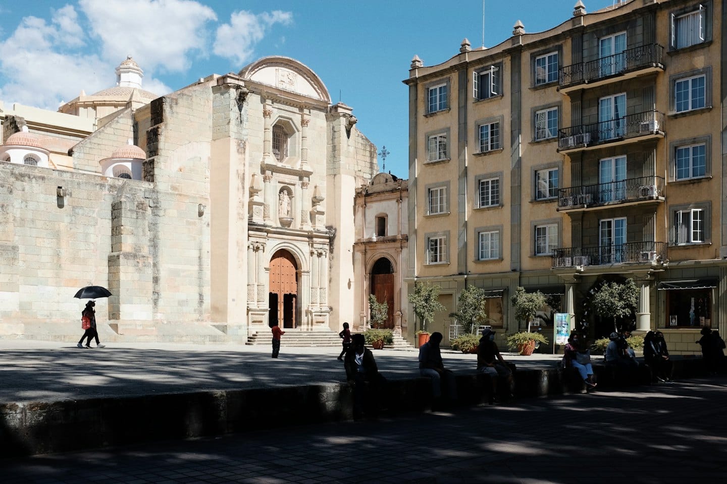 Persone camminano e siedono vicino a una storica chiesa di pietra.